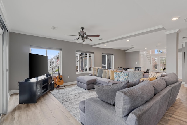 living room featuring light hardwood / wood-style flooring, a wealth of natural light, ceiling fan, and ornamental molding