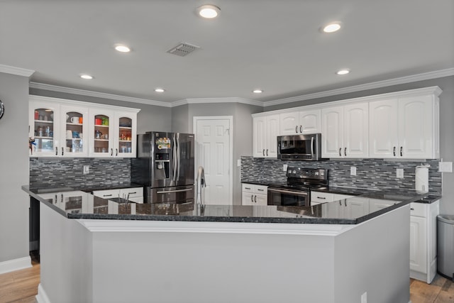 kitchen with white cabinets, tasteful backsplash, light wood-type flooring, dark stone counters, and stainless steel appliances