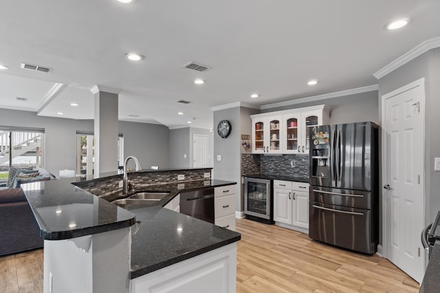 kitchen featuring beverage cooler, appliances with stainless steel finishes, a kitchen island, backsplash, and light hardwood / wood-style flooring