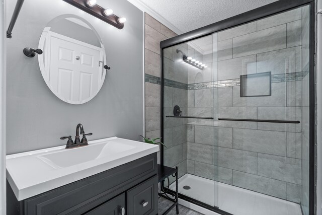 bathroom with a textured ceiling, an enclosed shower, vanity, and crown molding