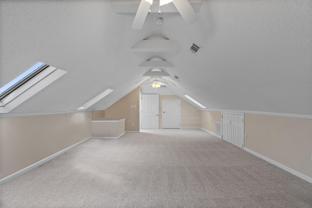 bonus room featuring ceiling fan, lofted ceiling with skylight, and light carpet