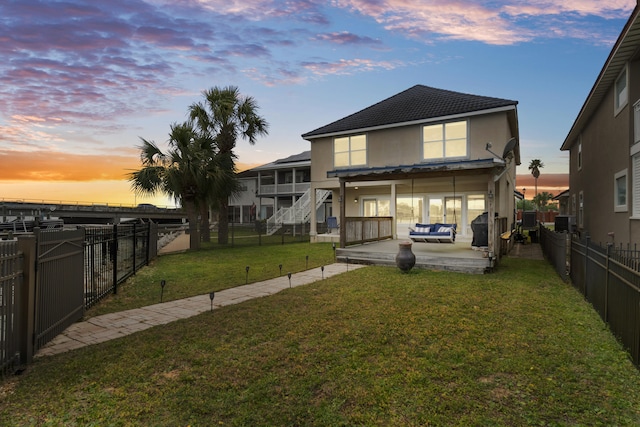 back house at dusk featuring a patio area, a yard, and central AC