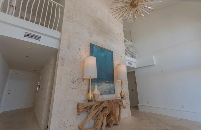 interior space with light tile floors, a chandelier, and a high ceiling