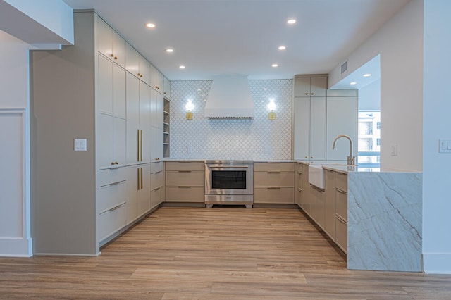 kitchen featuring light hardwood / wood-style flooring, tasteful backsplash, custom range hood, and range