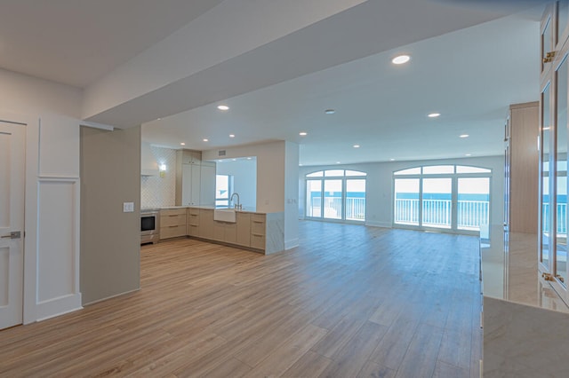 unfurnished living room with light hardwood / wood-style flooring and sink