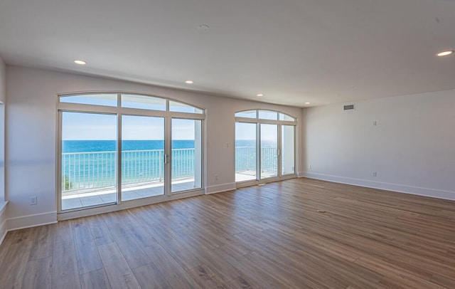 spare room featuring dark hardwood / wood-style flooring and a water view