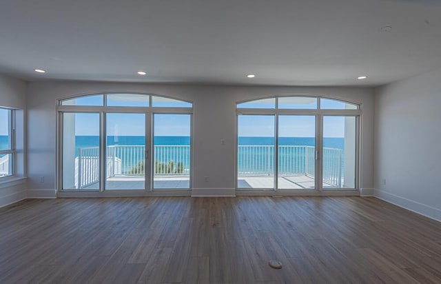 spare room featuring a water view and dark hardwood / wood-style floors