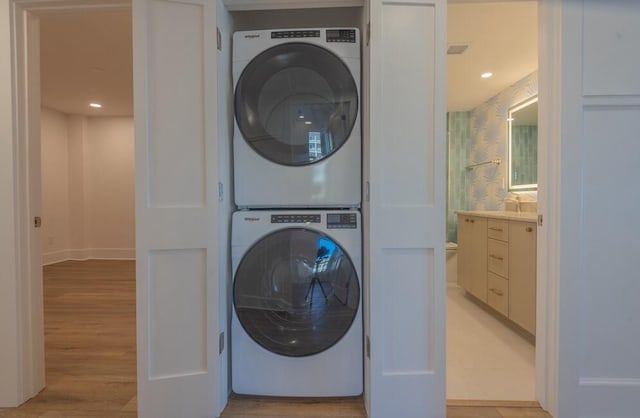 laundry area featuring sink, light wood-type flooring, and stacked washer and dryer