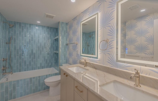 full bathroom featuring vanity with extensive cabinet space, tiled shower / bath combo, double sink, tile floors, and toilet