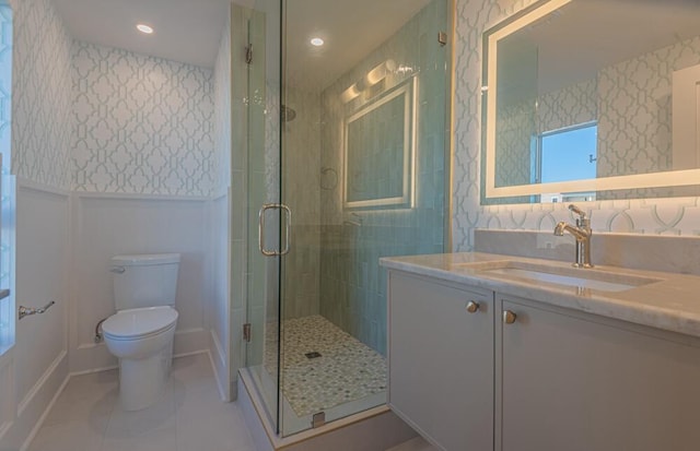 bathroom featuring a shower with door, tile floors, vanity, and toilet