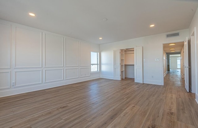 unfurnished bedroom featuring light hardwood / wood-style floors, a closet, and a walk in closet