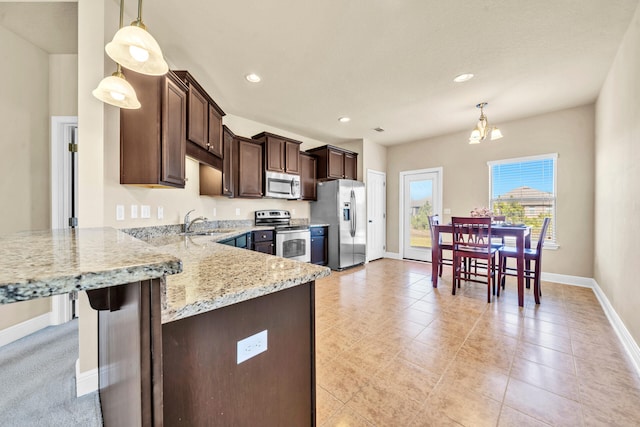 kitchen featuring sink, light stone counters, a chandelier, decorative light fixtures, and appliances with stainless steel finishes