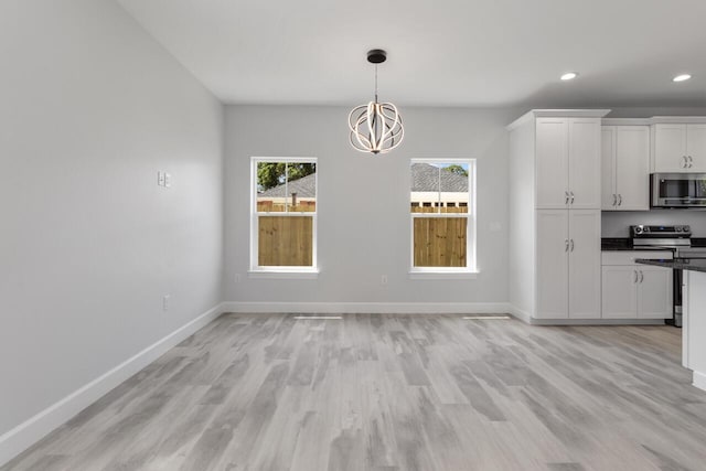 unfurnished dining area featuring an inviting chandelier and light wood-type flooring