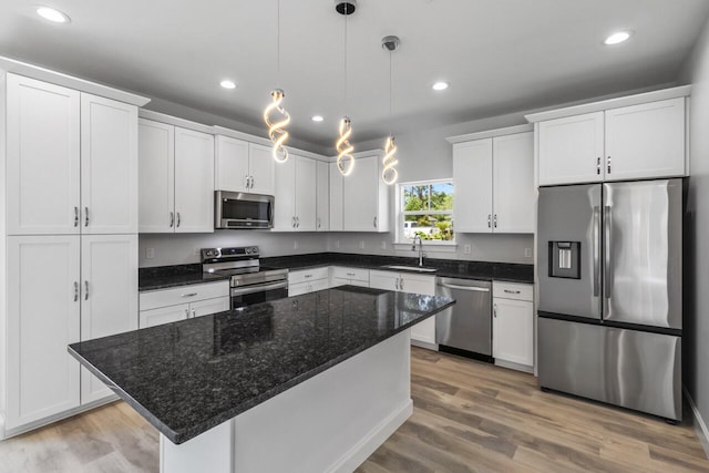 kitchen featuring a kitchen island, white cabinetry, appliances with stainless steel finishes, and decorative light fixtures