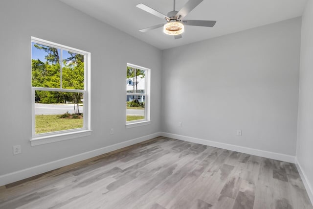 empty room featuring a wealth of natural light, ceiling fan, and light hardwood / wood-style flooring