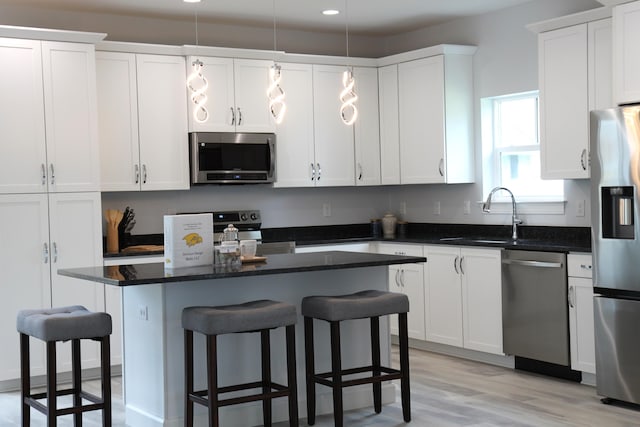 kitchen featuring a kitchen island, appliances with stainless steel finishes, a kitchen bar, sink, and white cabinets