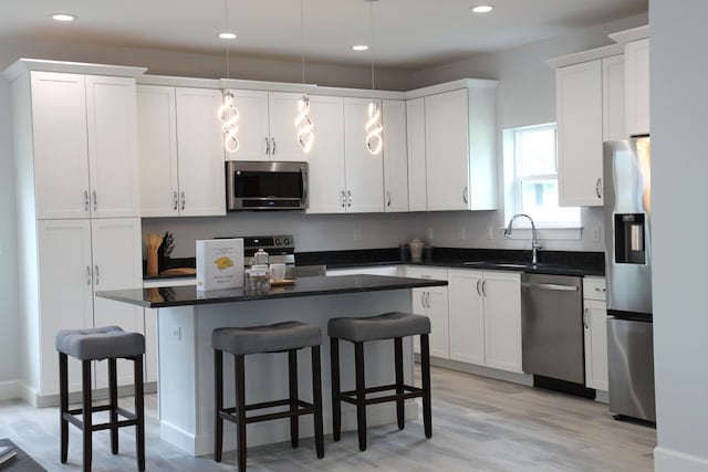 kitchen with white cabinetry, appliances with stainless steel finishes, pendant lighting, sink, and a center island