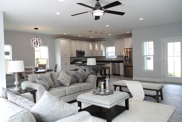 living room featuring a wealth of natural light, hardwood / wood-style flooring, and ceiling fan with notable chandelier