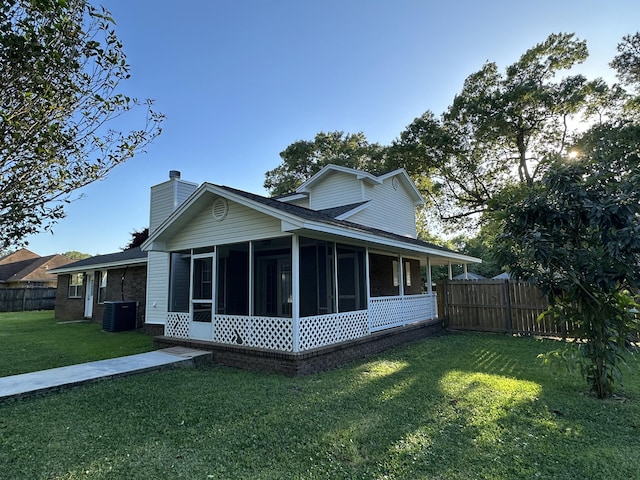 exterior space featuring central AC, a sunroom, and a lawn