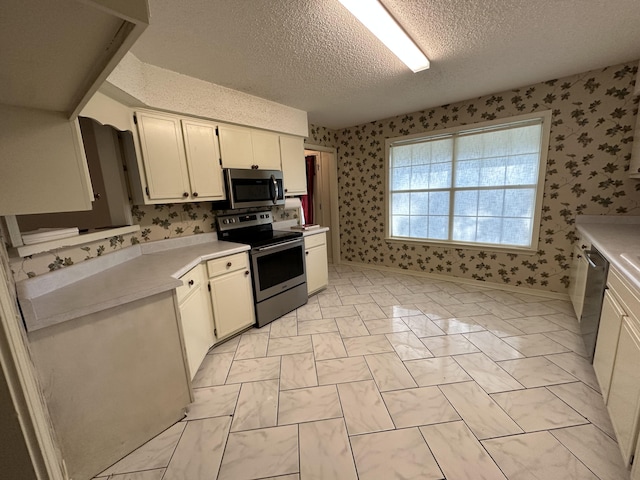 kitchen featuring white cabinets, stainless steel appliances, light tile floors, and a textured ceiling