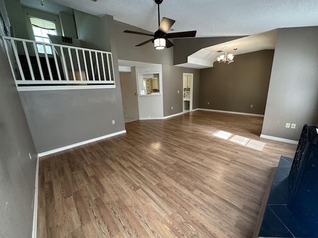 interior space featuring ceiling fan with notable chandelier, a textured ceiling, hardwood / wood-style floors, and high vaulted ceiling