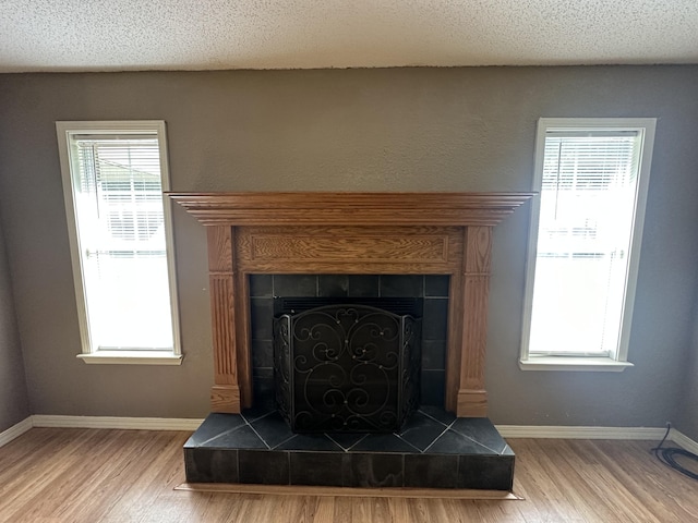 interior details featuring a textured ceiling, hardwood / wood-style floors, and a tile fireplace