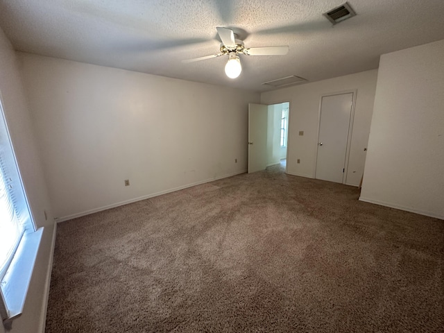 empty room featuring a textured ceiling, ceiling fan, and dark colored carpet