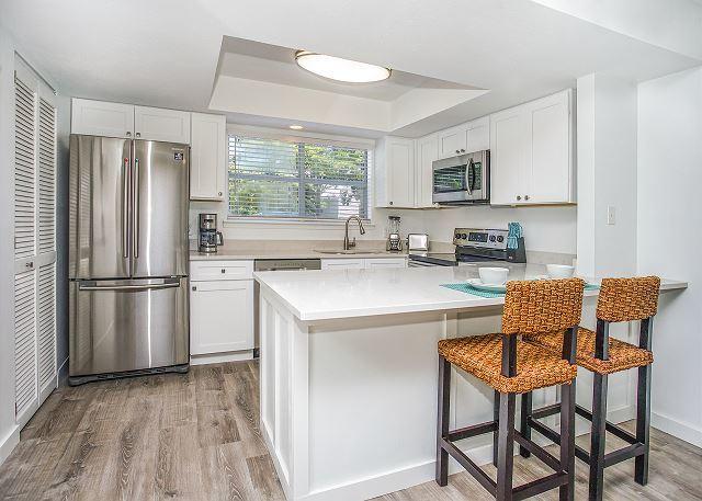 kitchen with appliances with stainless steel finishes, light hardwood / wood-style flooring, white cabinets, a kitchen breakfast bar, and a raised ceiling