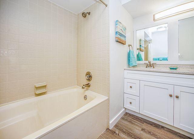 bathroom with hardwood / wood-style flooring, tiled shower / bath, and large vanity