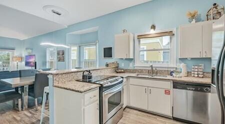 kitchen featuring white cabinets, appliances with stainless steel finishes, kitchen peninsula, and light hardwood / wood-style flooring