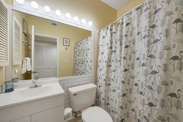 bathroom featuring tile walls, oversized vanity, and toilet