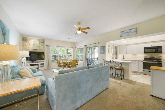 carpeted living room with sink and ceiling fan