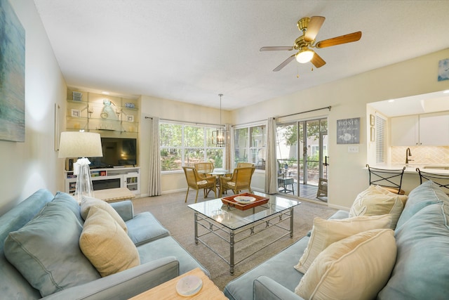 living room featuring light colored carpet, ceiling fan, and sink