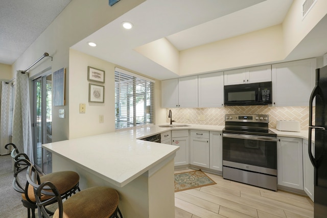 kitchen with a wealth of natural light, kitchen peninsula, sink, and black appliances