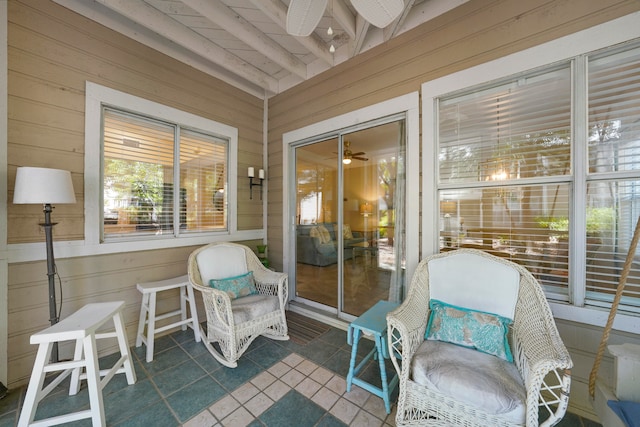 sunroom / solarium featuring beam ceiling and ceiling fan