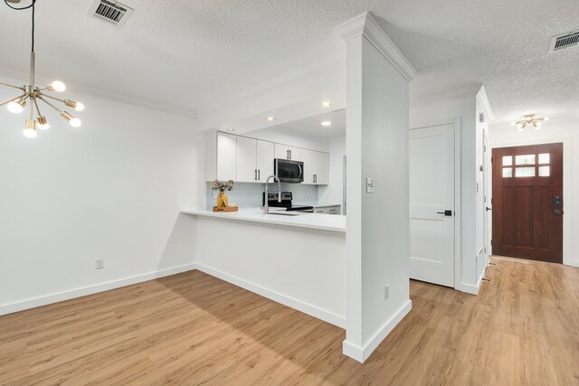 kitchen with white cabinets, a textured ceiling, stainless steel appliances, and light hardwood / wood-style floors