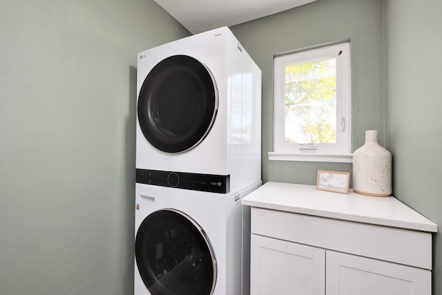 washroom with cabinets and stacked washer and dryer