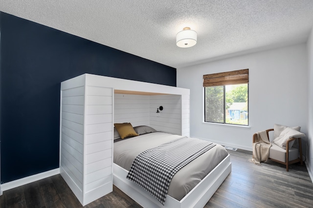 bedroom with dark hardwood / wood-style floors and a textured ceiling