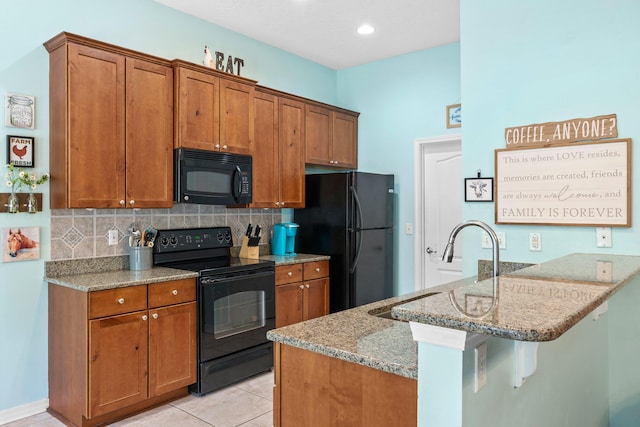 kitchen featuring kitchen peninsula, light stone countertops, black appliances, tasteful backsplash, and light tile floors