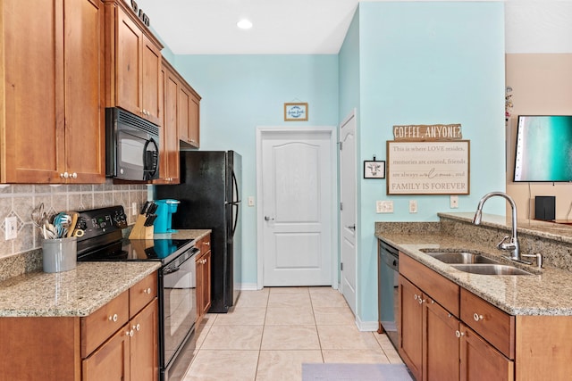 kitchen featuring light stone countertops, black appliances, backsplash, light tile floors, and sink