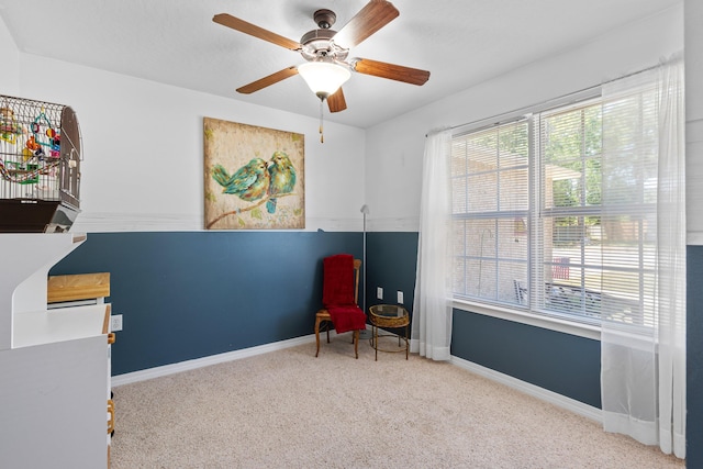 living area featuring light carpet and ceiling fan