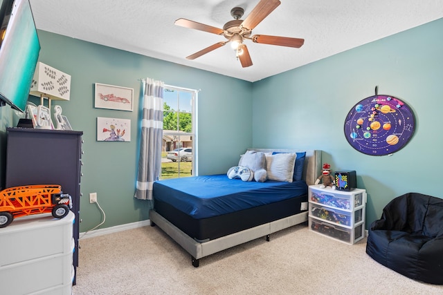 carpeted bedroom featuring ceiling fan and a textured ceiling