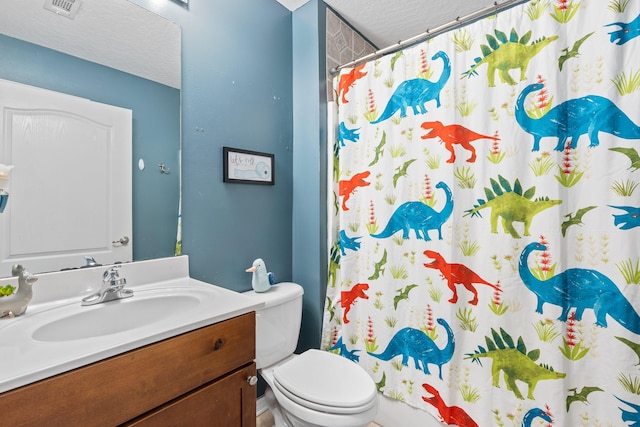 bathroom with a textured ceiling, vanity, and toilet