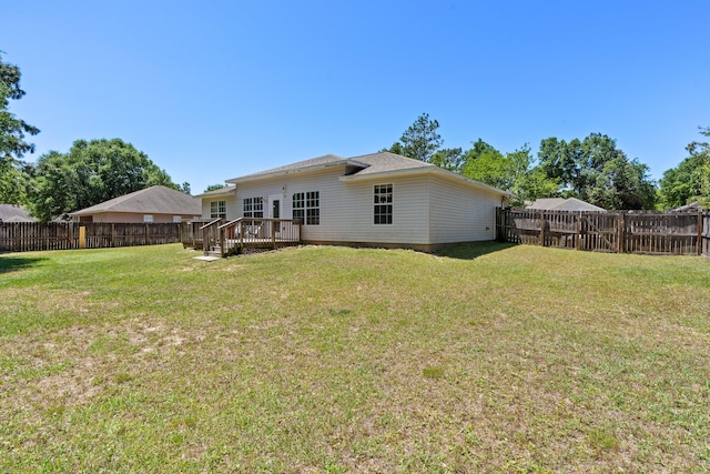 back of property with a wooden deck and a lawn