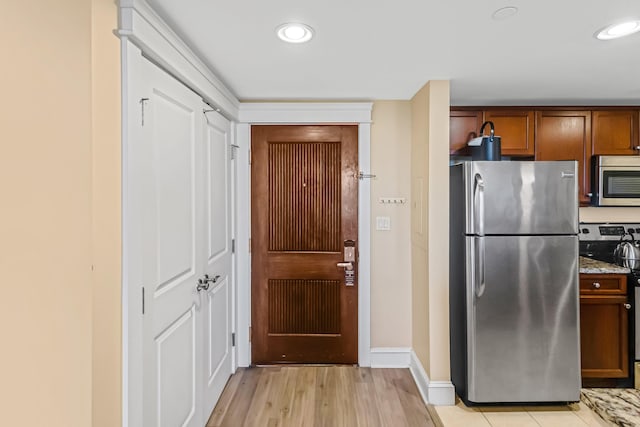 kitchen featuring light stone counters, light hardwood / wood-style flooring, and stainless steel appliances