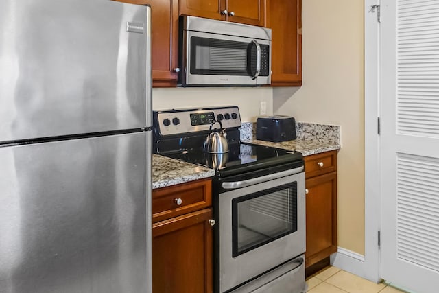 kitchen featuring appliances with stainless steel finishes, light stone countertops, and light tile flooring