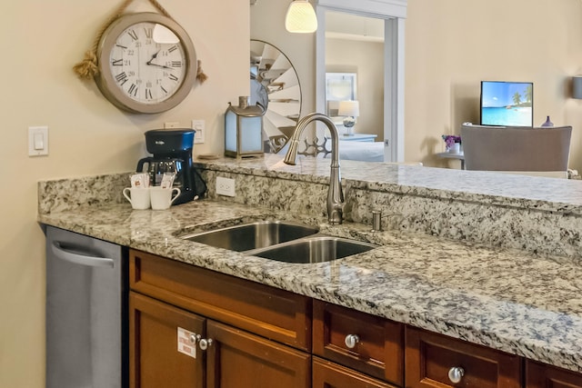 kitchen featuring light stone counters, sink, and stainless steel dishwasher