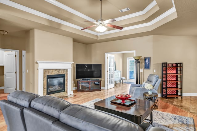 living room featuring a raised ceiling, ceiling fan, crown molding, and hardwood / wood-style flooring