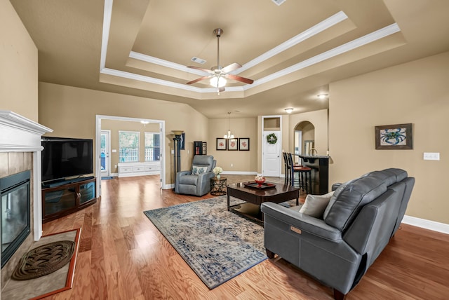 living room with a fireplace, a raised ceiling, and light hardwood / wood-style floors