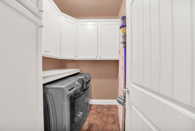 washroom featuring cabinets, dark tile flooring, and washer and dryer